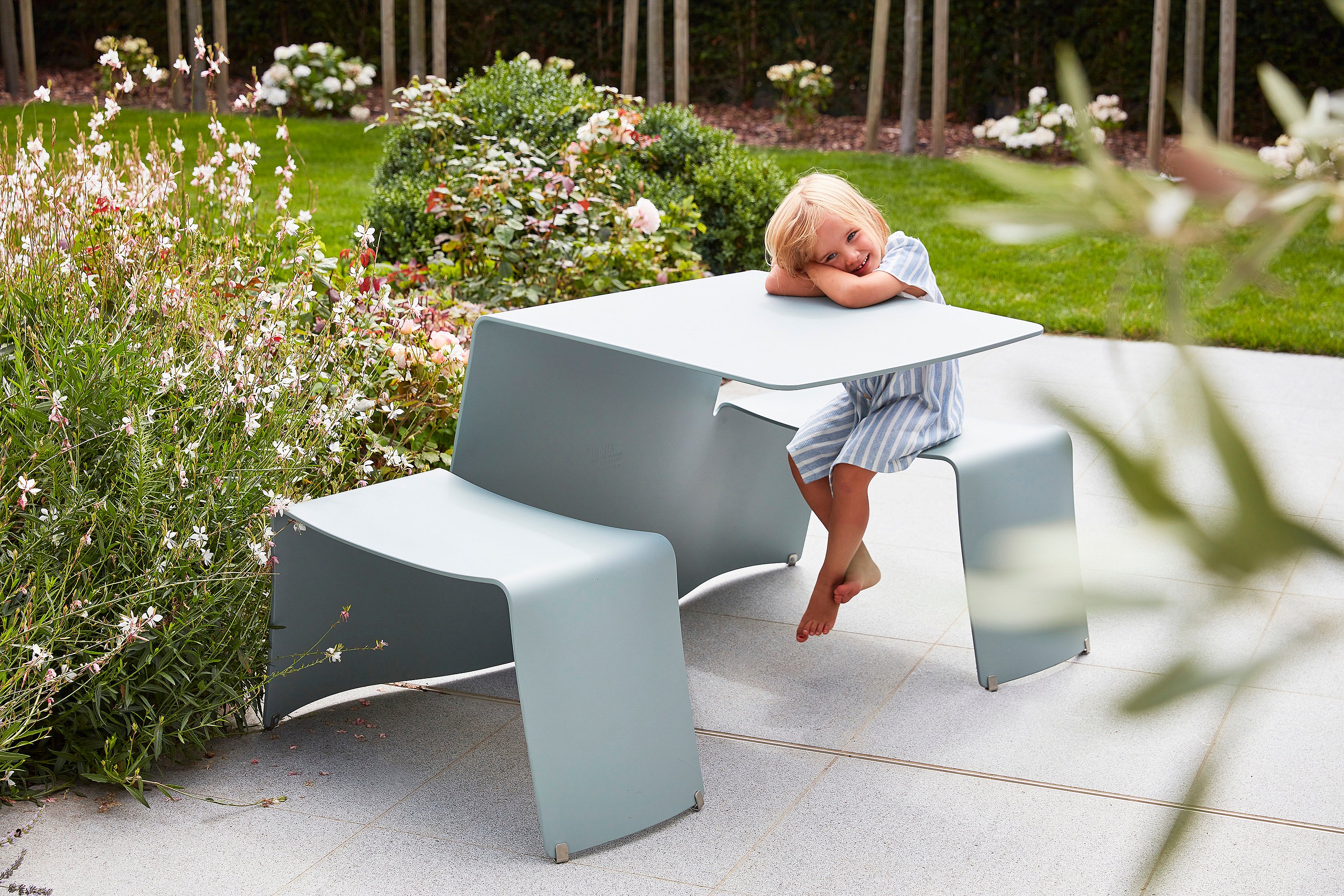 Picknicktafel naast kleurrijke, geurende bloemen, een favoriete plek voor het jongste gezinslid.