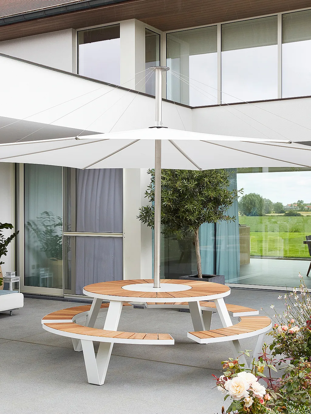 Sonnige Familienterrasse in Pollinkhove, Belgien, ausgestattet mit verschiedenen Extremis-Gartenmöbeln, darunter Sofa, Tisch und Sonnenschirm.