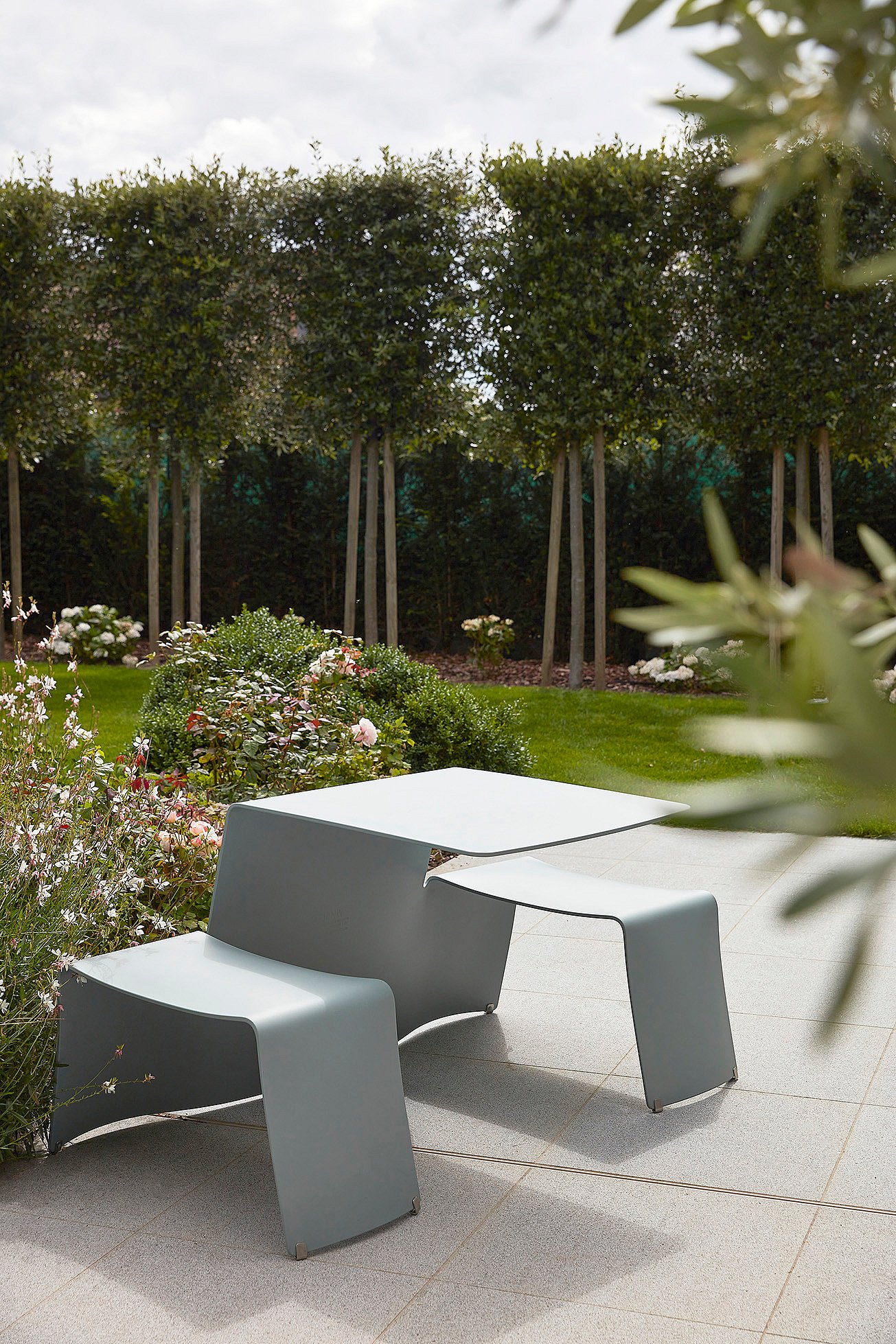 Tuindetails met bloeiende planten bij de picknicktafel.