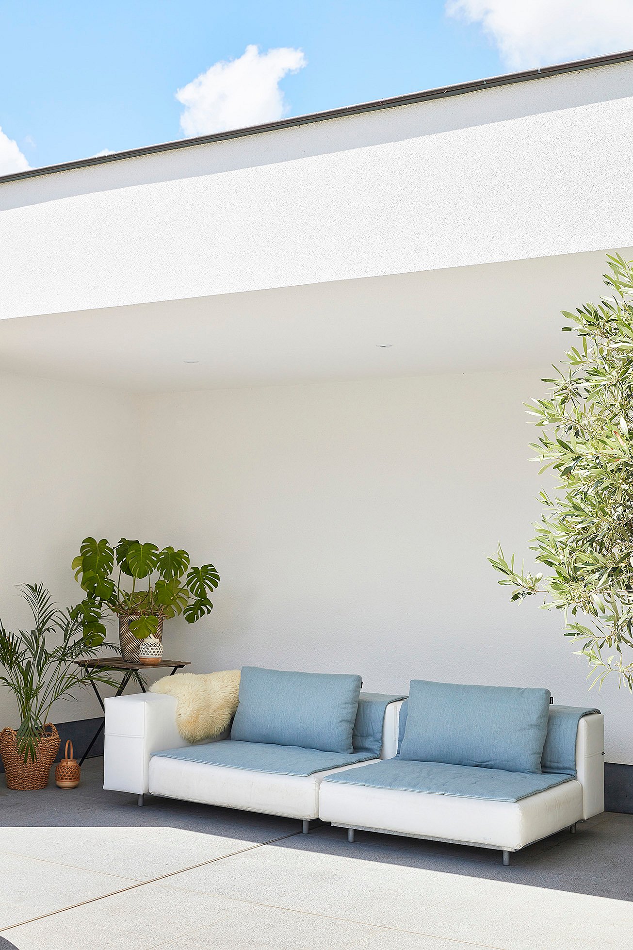   De grijze Walrus tuinbank met zachte kussens, perfect geplaatst om comfortabel in de zon te loungen.