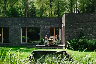 La douce finition vert pistache de la table de pique-nique Manille et des plateaux en bois de ses bancs contraste avec le feuillage du jardin, créant une ambiance calme et harmonieuse.