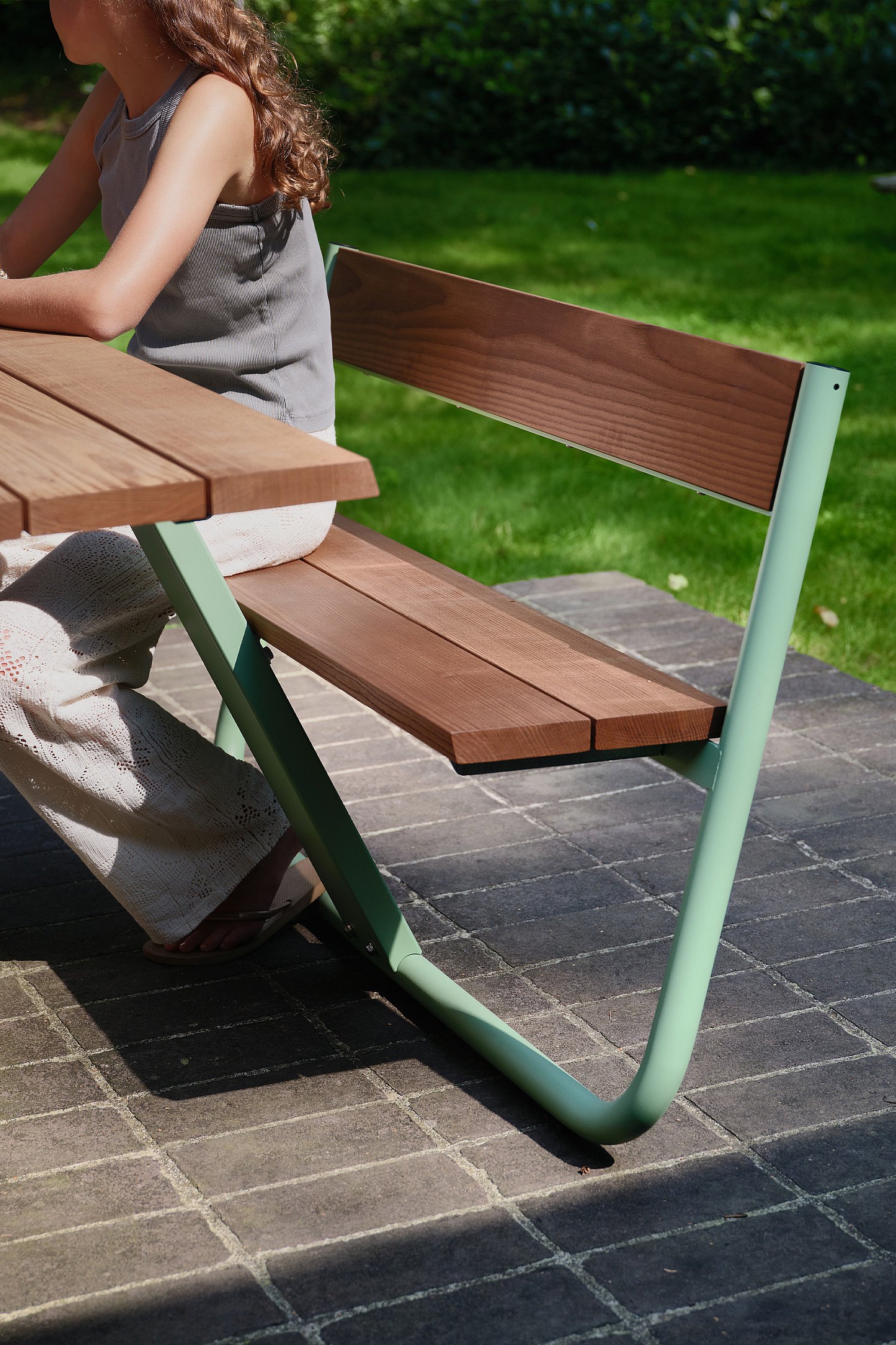 Gros plan sur les bancs et dossiers intégrés de la table Manille, illustrant le confort du design et son harmonie avec la végétation environnante.