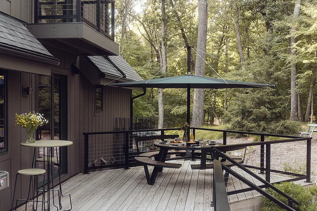 Wide view of an outdoor terrace in Michiana Shores with several round and outdoor tables and benches arranged on a light wooden deck.