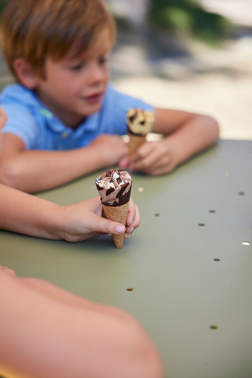 De kinderen zitten op de Virus tafel en genieten van een ijsje.