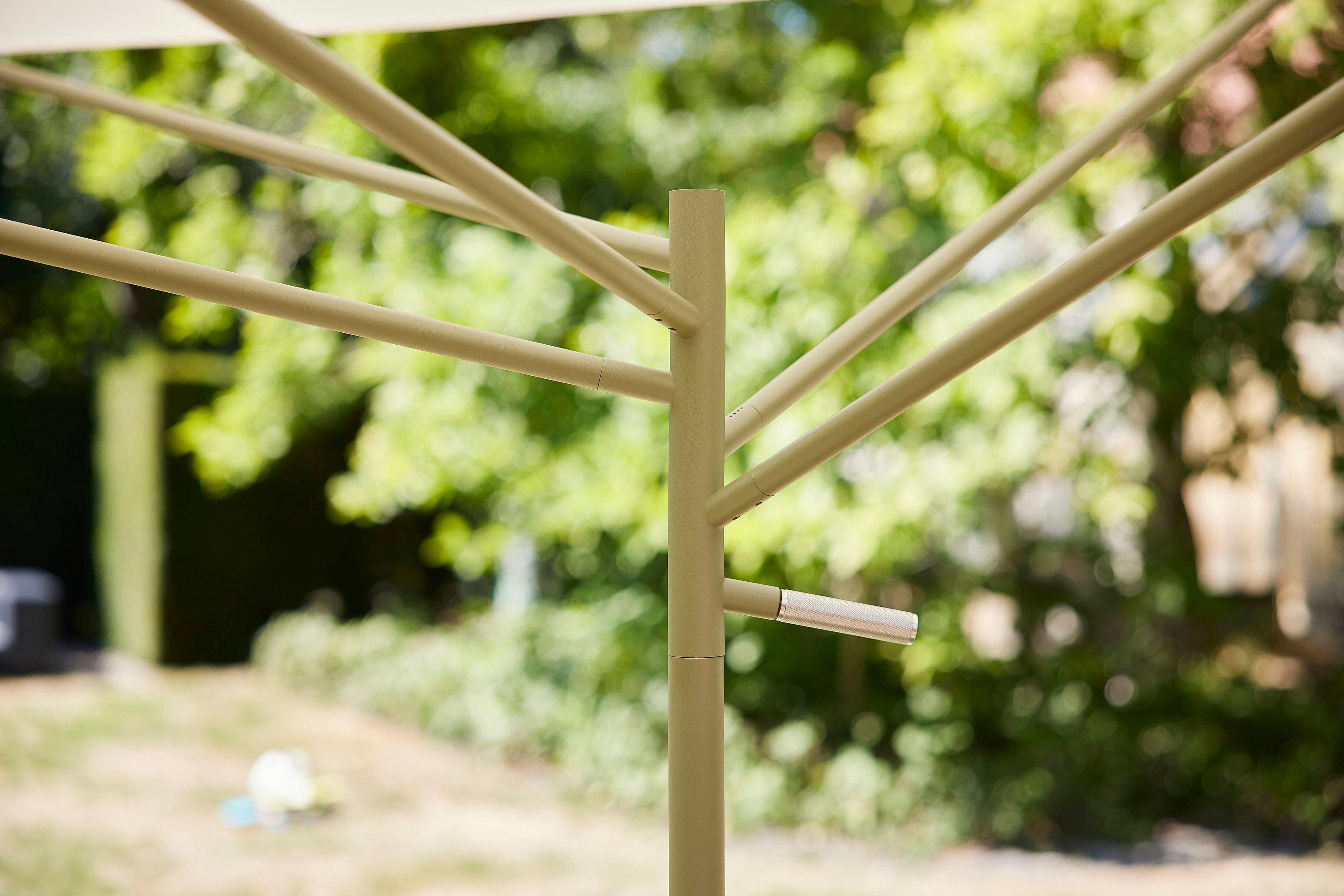 Close-up van het groene frame met de centrale paal en meerdere steunarmen die naar buiten stralen, met een klein metalen handvat aan de zijkant.