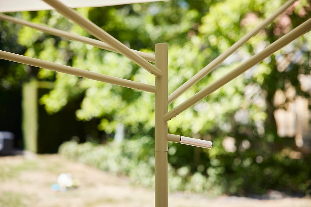 Close-up van het groene frame met de centrale paal en meerdere steunarmen die naar buiten stralen, met een klein metalen handvat aan de zijkant.