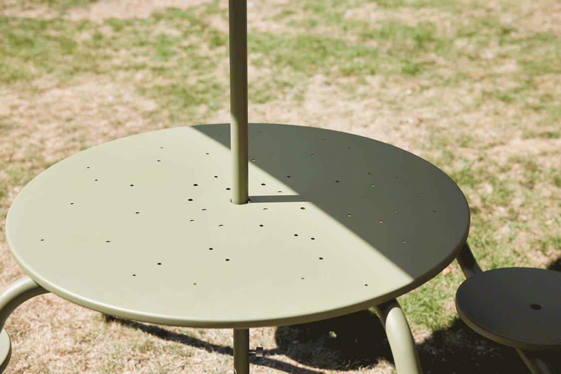 Schuin tuinaanzicht van een Virus picknicktafel met geïntegreerde banken in een grasveld.