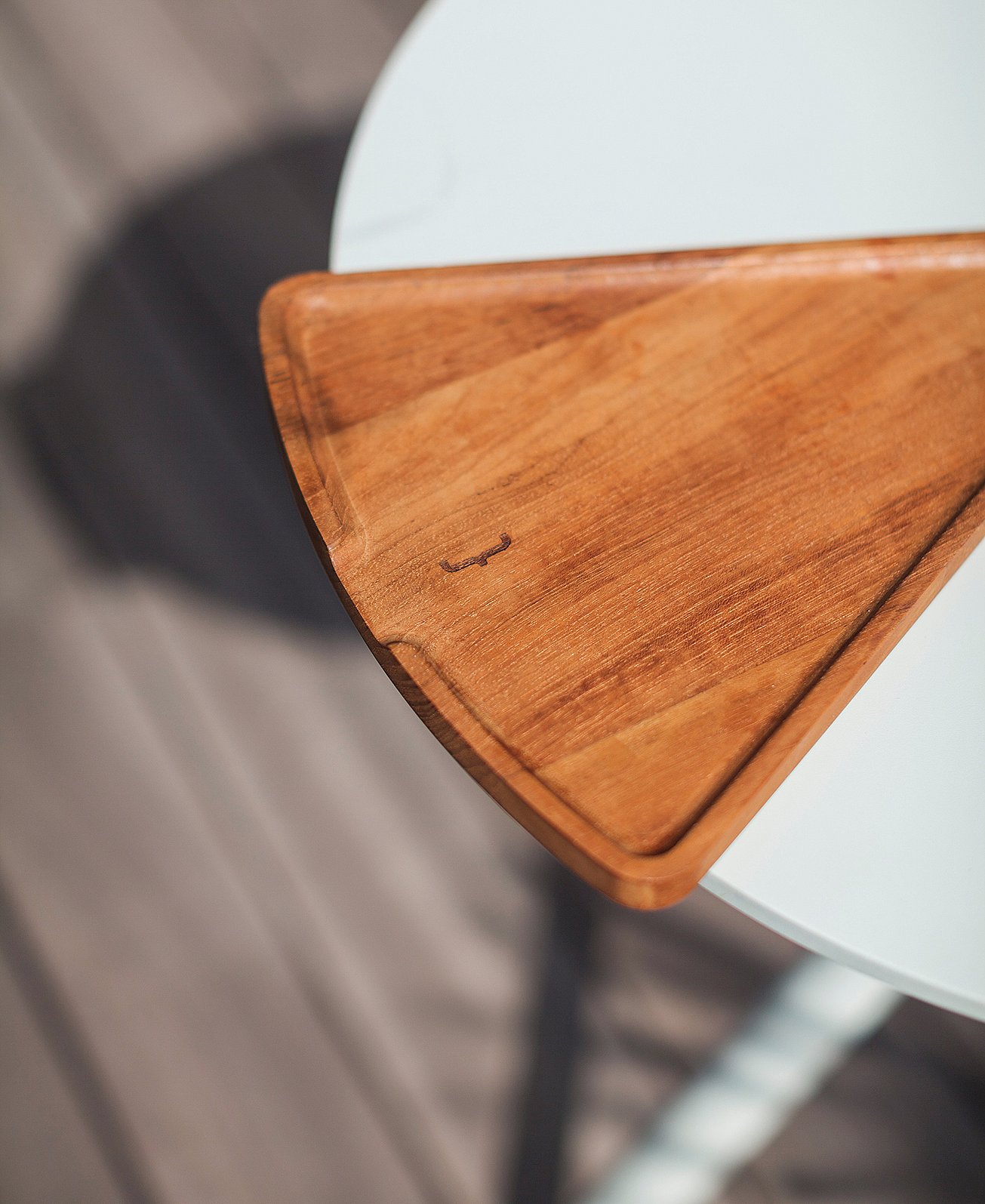 Close-up van een driehoekig houten dienblad dat op de rand van een ronde witte Bistroo-tafel rust.