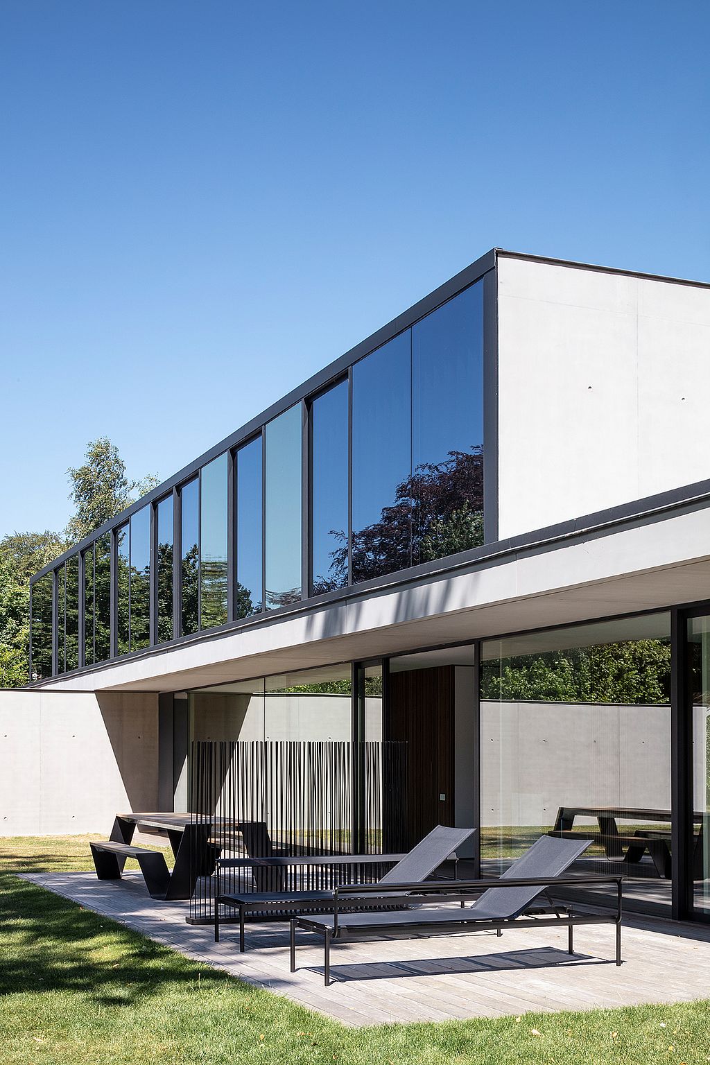 Terrasse avec mobilier de jardin foncé, se détachant sur un paysage champêtre ouvert et soulignant le contraste entre le mobilier moderne et la vue imprenable sur la campagne.