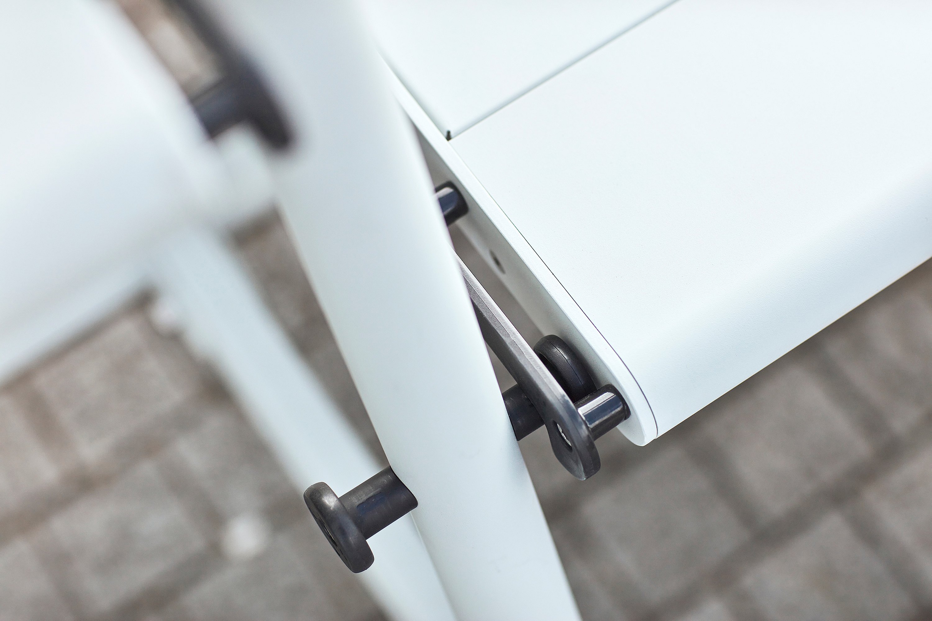 Close up of a turning knob and locking mechanism on the white Tiki table frame.