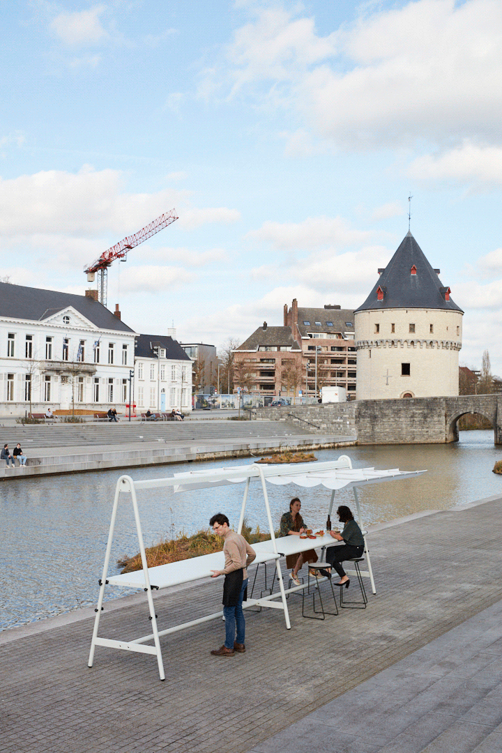 Vertical overview of the riverside dining setup with the Broel Tower and a construction crane visible across the river.