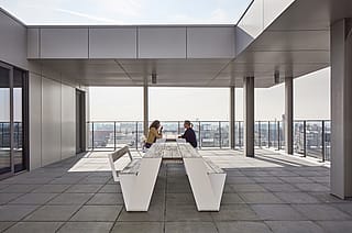 Scene showing more Hopper picnic tables and benches at Arhus library, with visitors enjoying the public space near the building’s entrances.