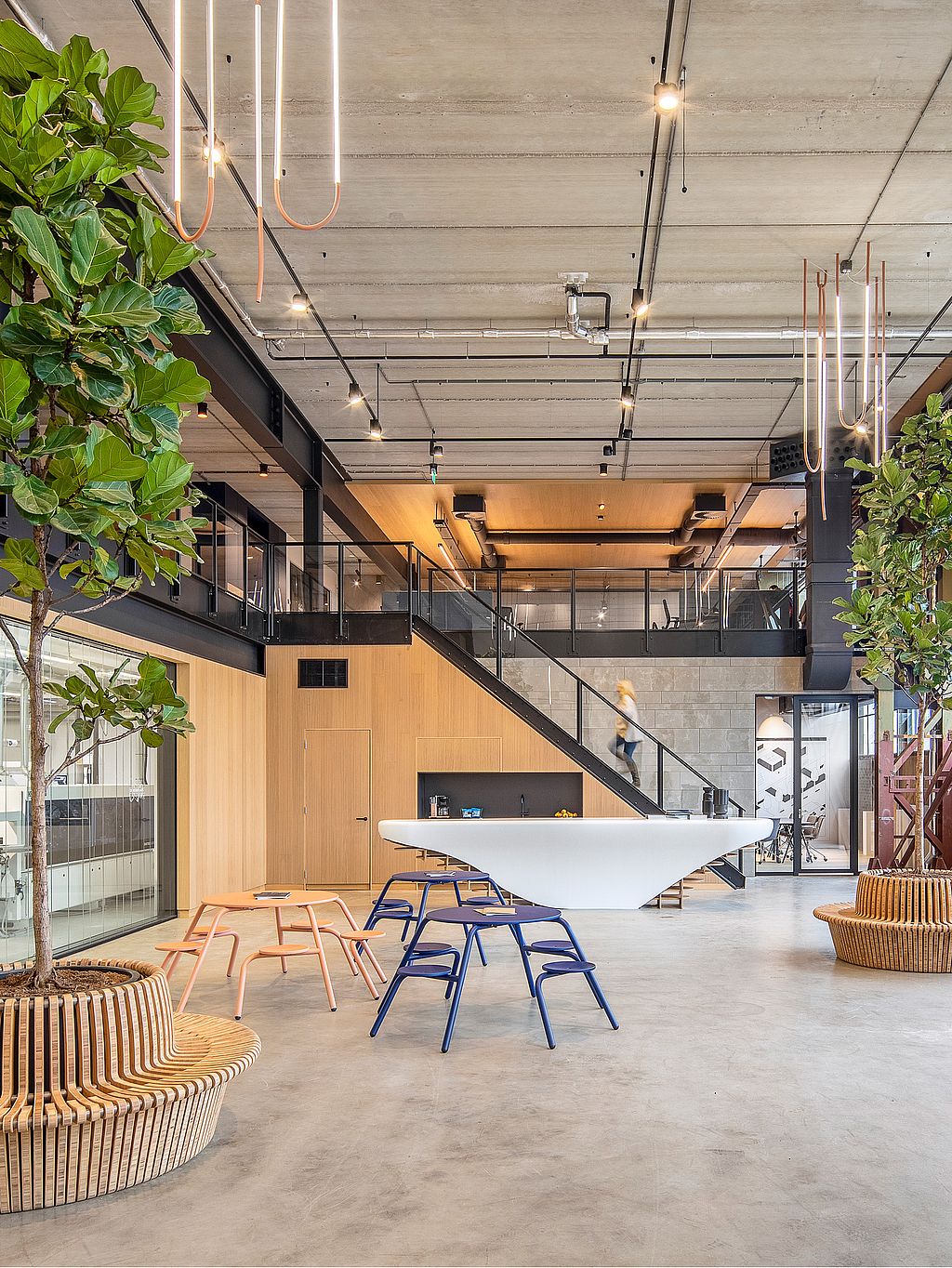 Vue d'ensemble de l'atelier montrant plusieurs tables et chaises disposées en îlots, permettant de collaborer dans une pièce lumineuse et ouverte.