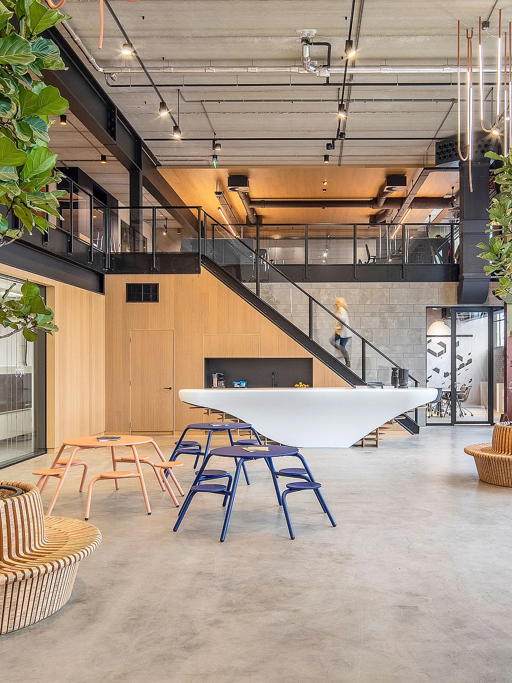 Vue d'ensemble de l'atelier montrant plusieurs tables et chaises disposées en îlots, permettant de collaborer dans une pièce lumineuse et ouverte.