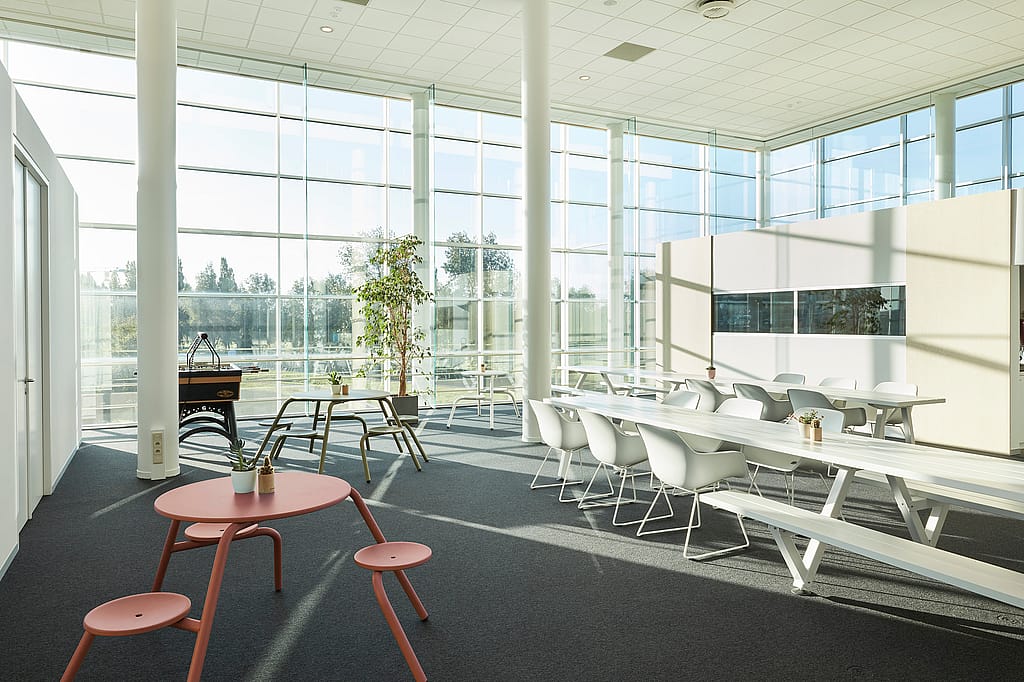 Ruim interieurbeeld van de eetruimte van de CCV-kantoren, met lange Marina-tafels en -banken; grote ramen en moderne kantoorverlichting creëren een lichte, collaboratieve omgeving.