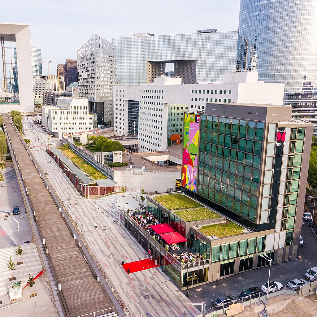 Terrassenansicht des citizenM Paris mit Sitzgruppen, Hotelgebäude und Stadtkulisse im Hintergrund.
