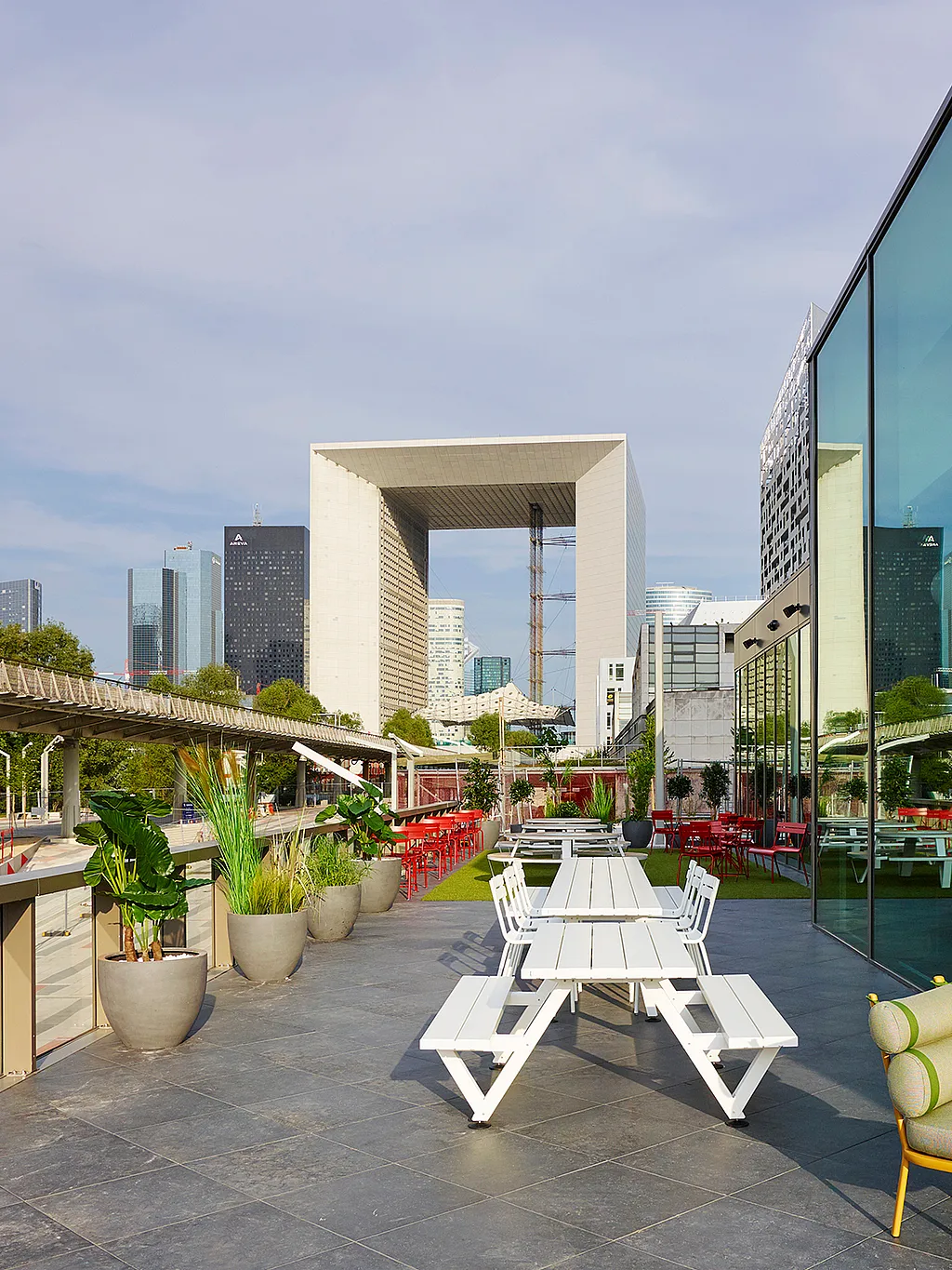 Vue extérieure panoramique de l'hôtel citizenM Paris, un établissement moderne situé à La Défense. Sa façade entièrement vitrée reflète la lumière et la silhouette de la ville.