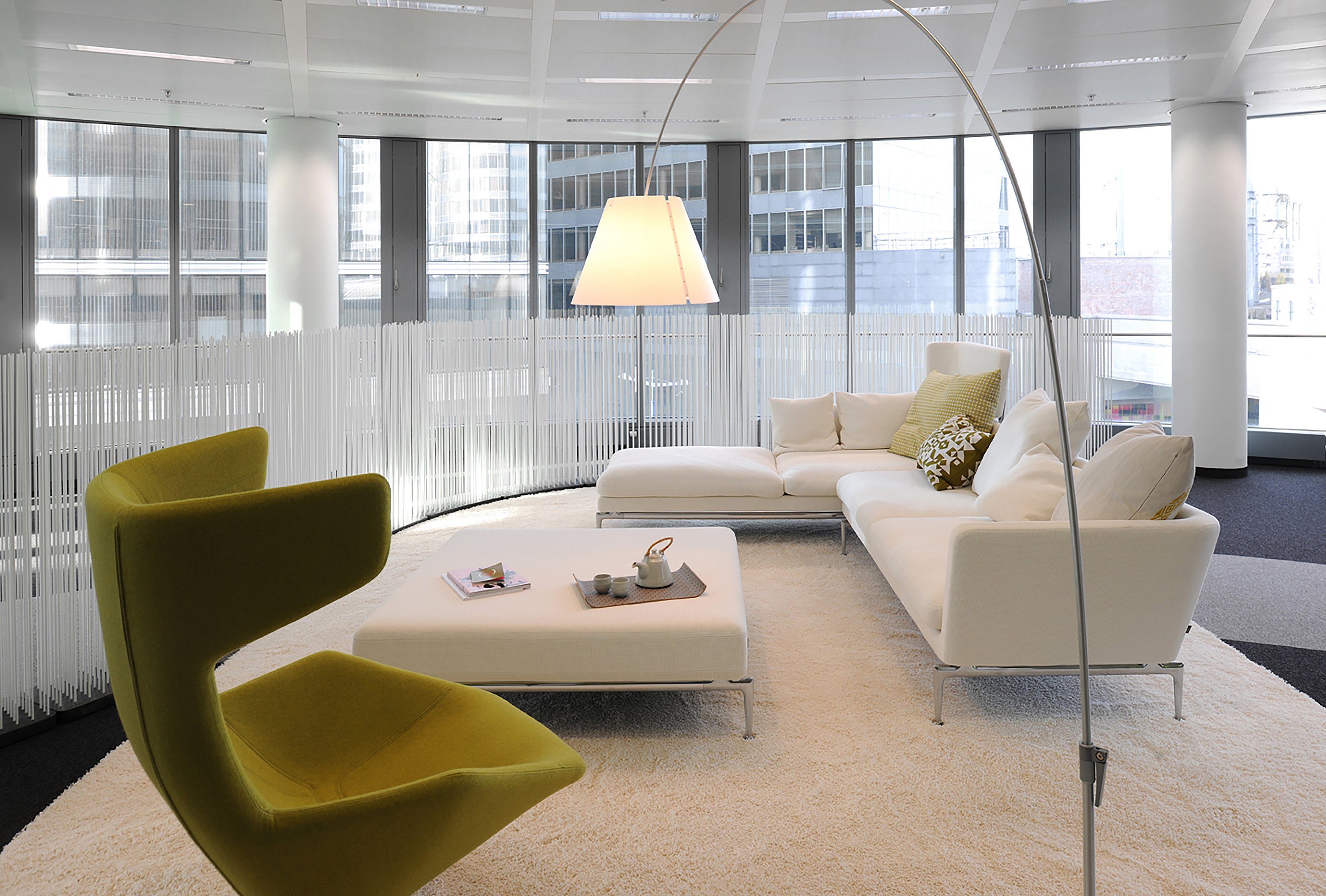   Zeitgenössische Büroräume mit Lounge-Sitzgruppen und Tischen, die durch hohe Extremis Sticks unterteilt sind und so flexible Grenzen zwischen verschiedenen Funktionsbereichen schaffen.