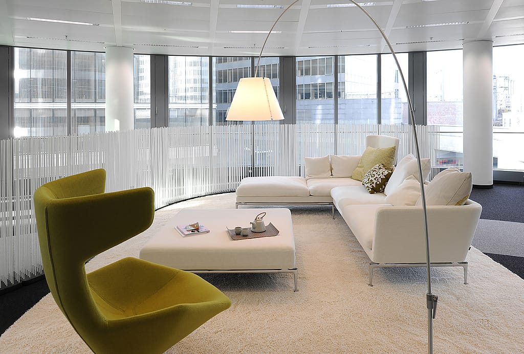 Zeitgenössische Büroräume mit Lounge-Sitzgruppen und Tischen, die durch hohe Extremis Sticks unterteilt sind und so flexible Grenzen zwischen verschiedenen Funktionsbereichen schaffen.