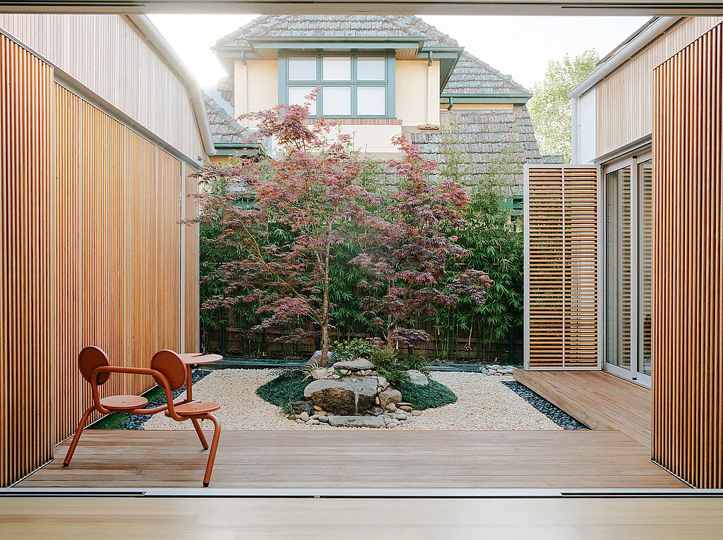 Timber-lined courtyard of a minimalist Melbourne home with a Japanese maple tree at the center and a copper-brown Bistroo table set placed on the terrace.