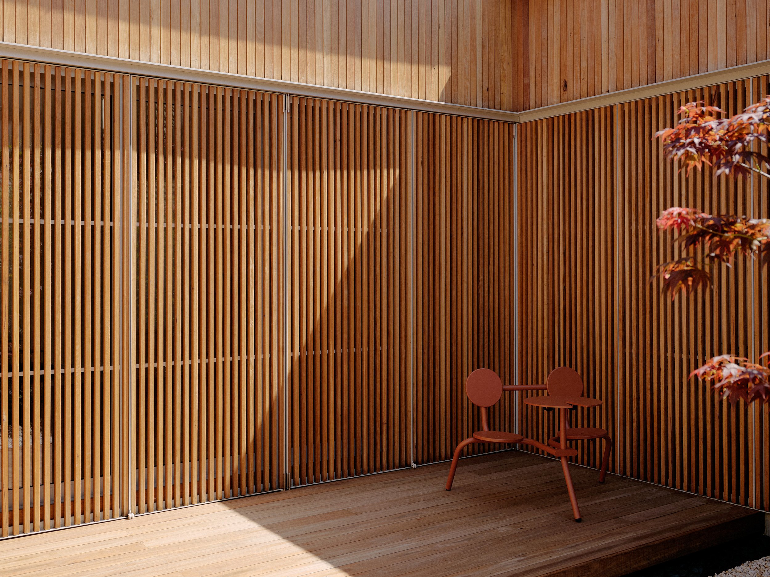   Cour intérieure minimaliste aux surfaces chaleureuses en bois et à la végétation luxuriante, conçue autour d'un arbre central pour créer un havre de paix extérieur.