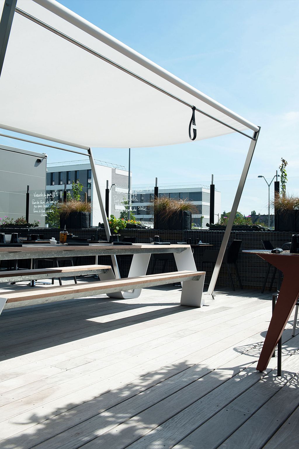 Die geräumige Terrasse bietet Hopper-Tische und -Bänke für Gruppenessen im Schatten der Sonnenschirme.