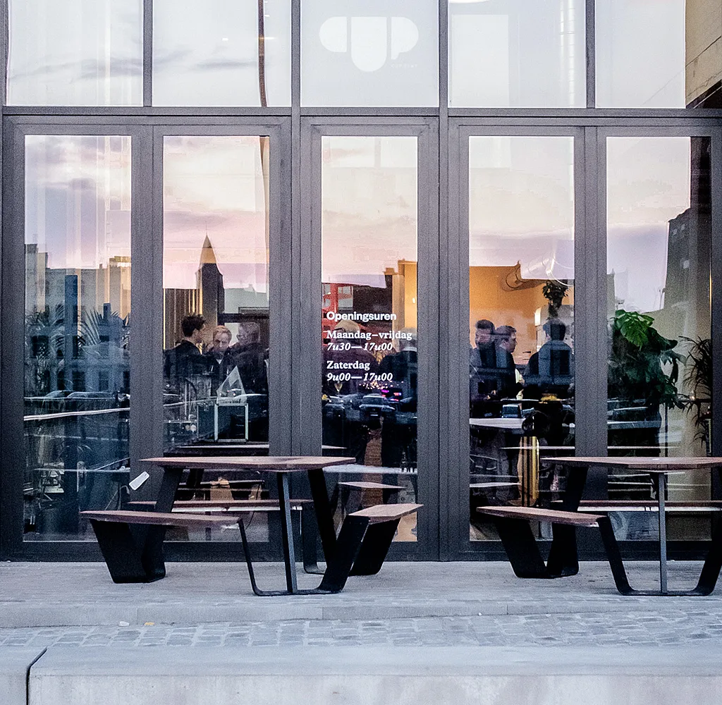 Outdoor terrace at CUP Ghent with Anker table arranged for guests enjoying drinks and snacks in a lively sports-oriented café setting.