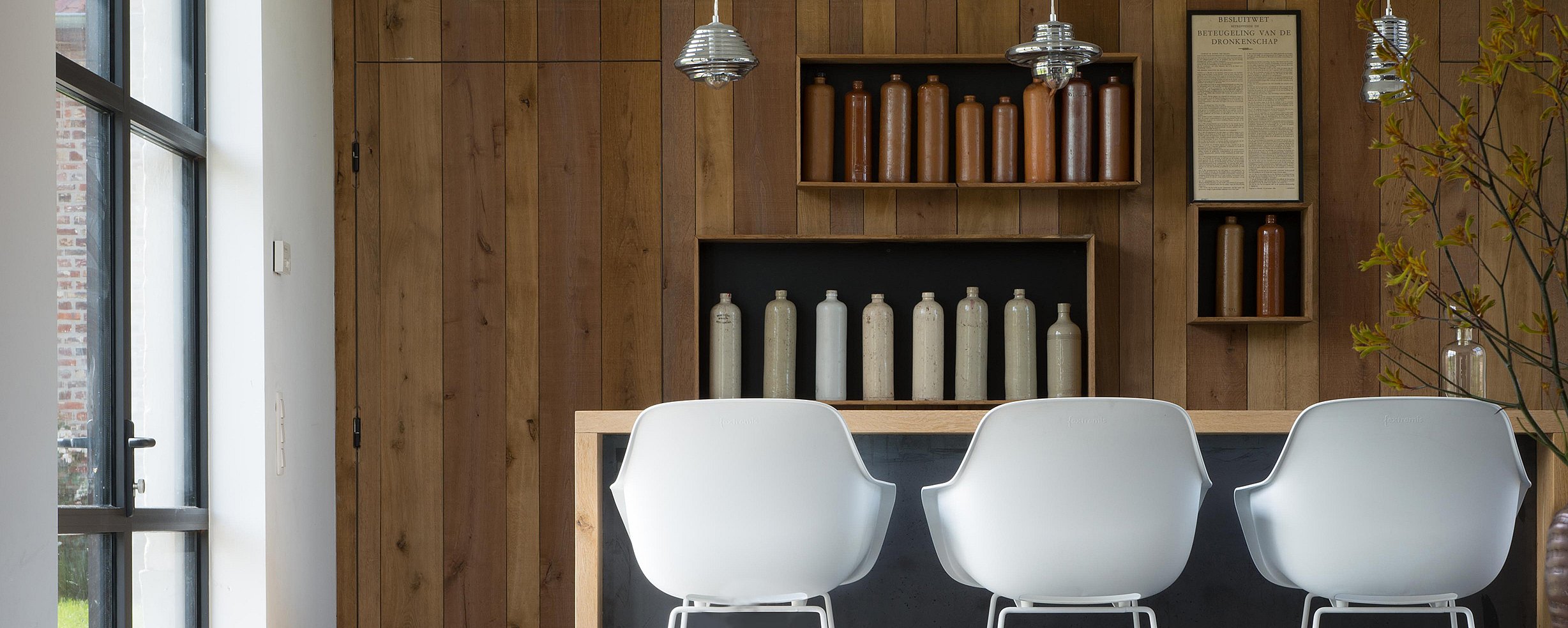  Close-up van een witte Captain's Chair naast een houten tafel in de schuur, die het contrast tussen modern design en rustieke materialen benadrukt.