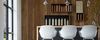 Close-up van een witte Captain's Chair naast een houten tafel in de schuur, die het contrast tussen modern design en rustieke materialen benadrukt.