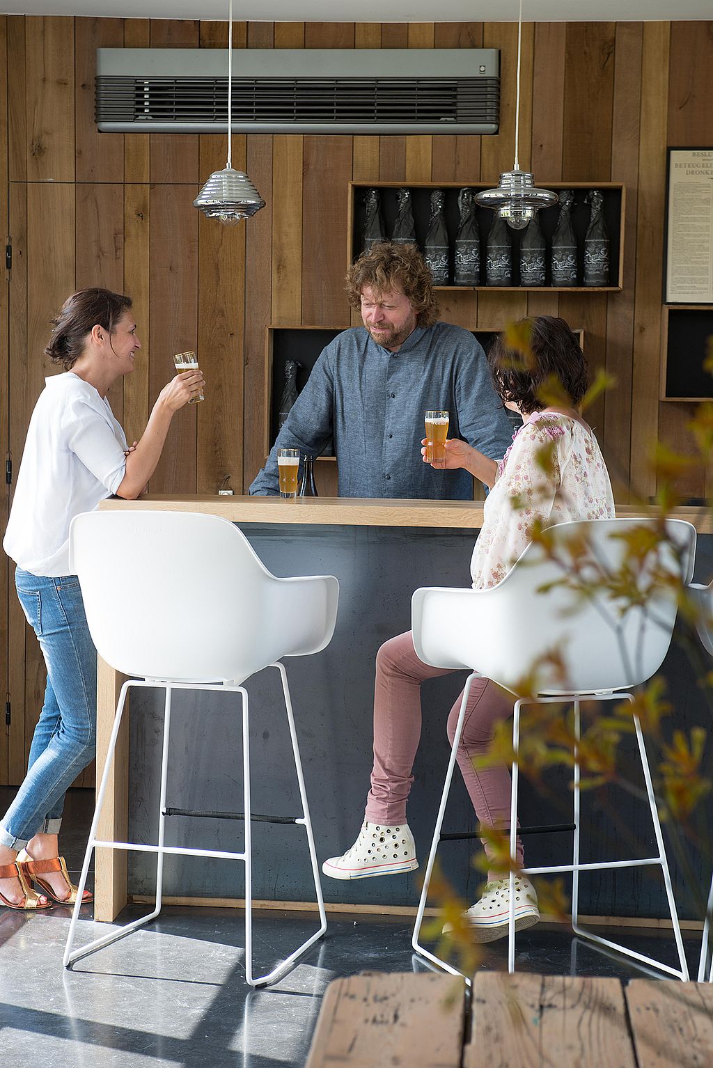Gasten praten en delen drankjes rond de bar en zitten op de Captain's Chairs in de gerenoveerde schuur als evenementenruimte.