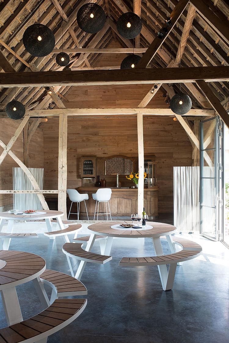 Uitzicht door het moderne interieur van de schuur, waarbij het contrast tussen donkere houten balken en modern wit meubilair wordt benadrukt.