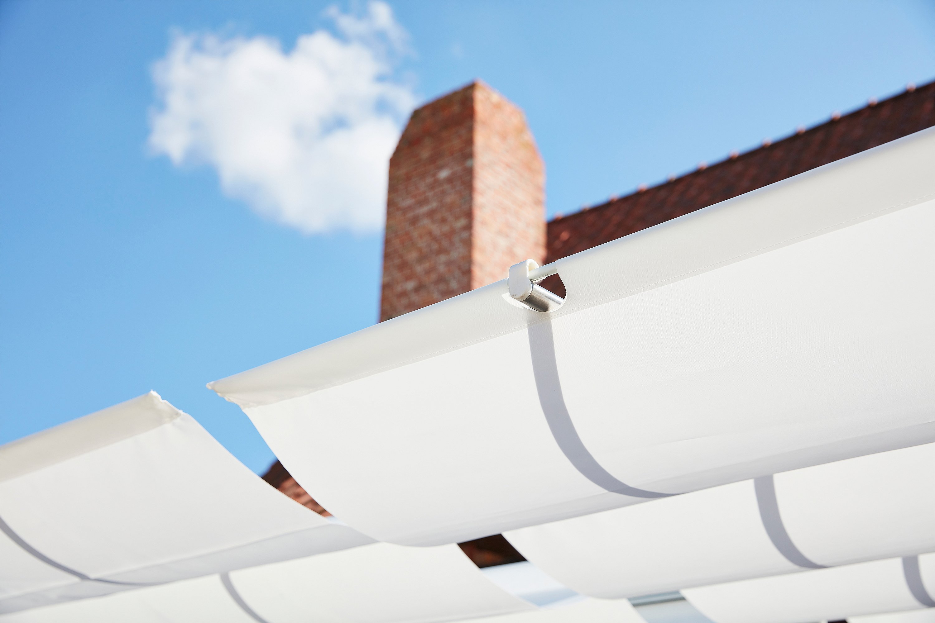 “Witte stoffen zonneschaduwpanelen gespannen over de A-frame structuur van de AMAi buitentafel. ”