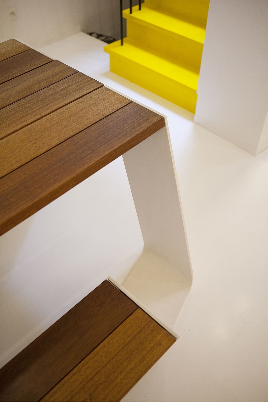 Gros plan sur la table de pique-nique Hopper, avec son plateau à lattes de bois et ses pieds de banc inclinés, dans cet intérieur lumineux.