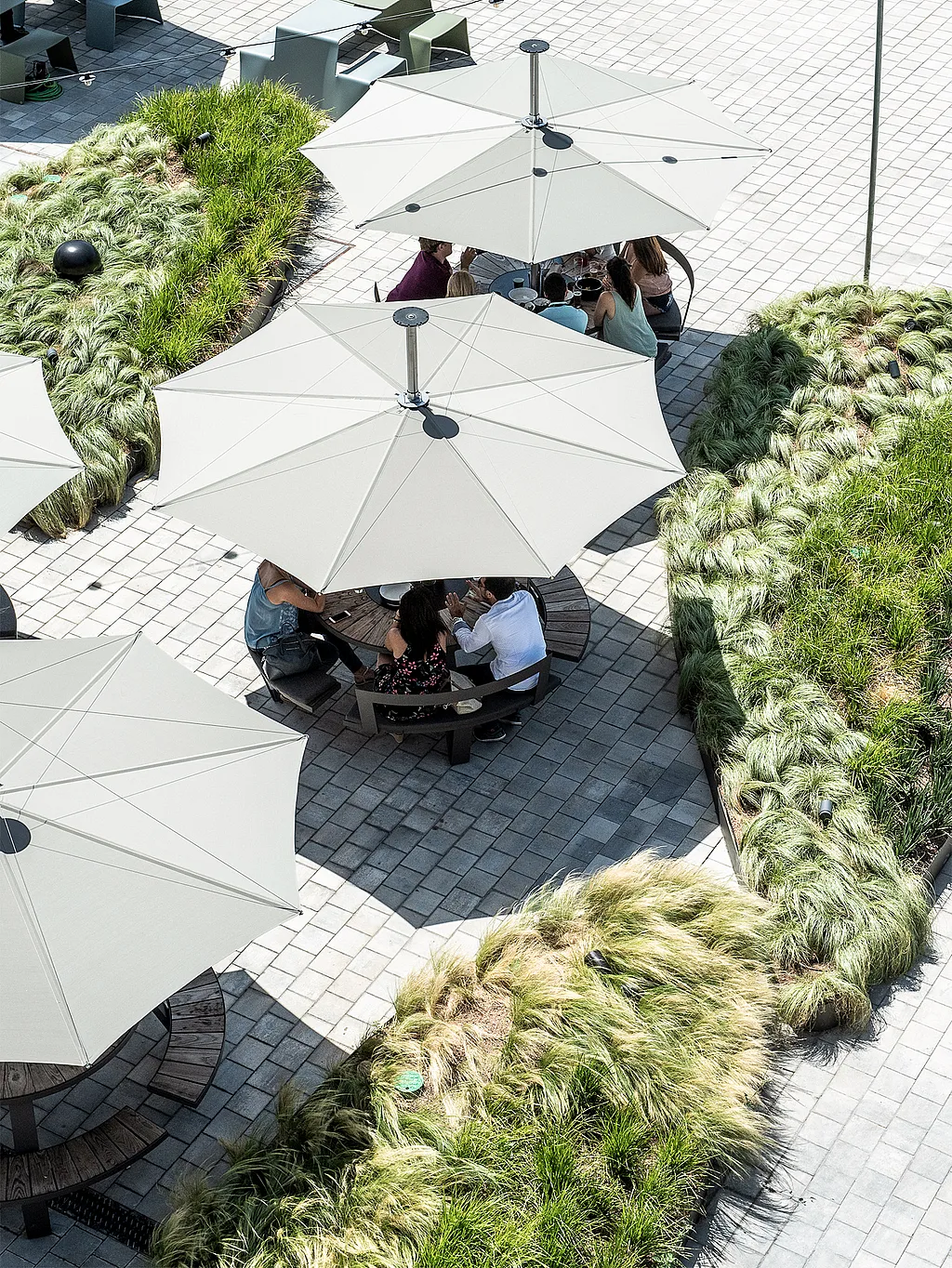 “Restaurant terrace in Barcelona with round Pantagruel picnic tables under large white Inumbra shades
