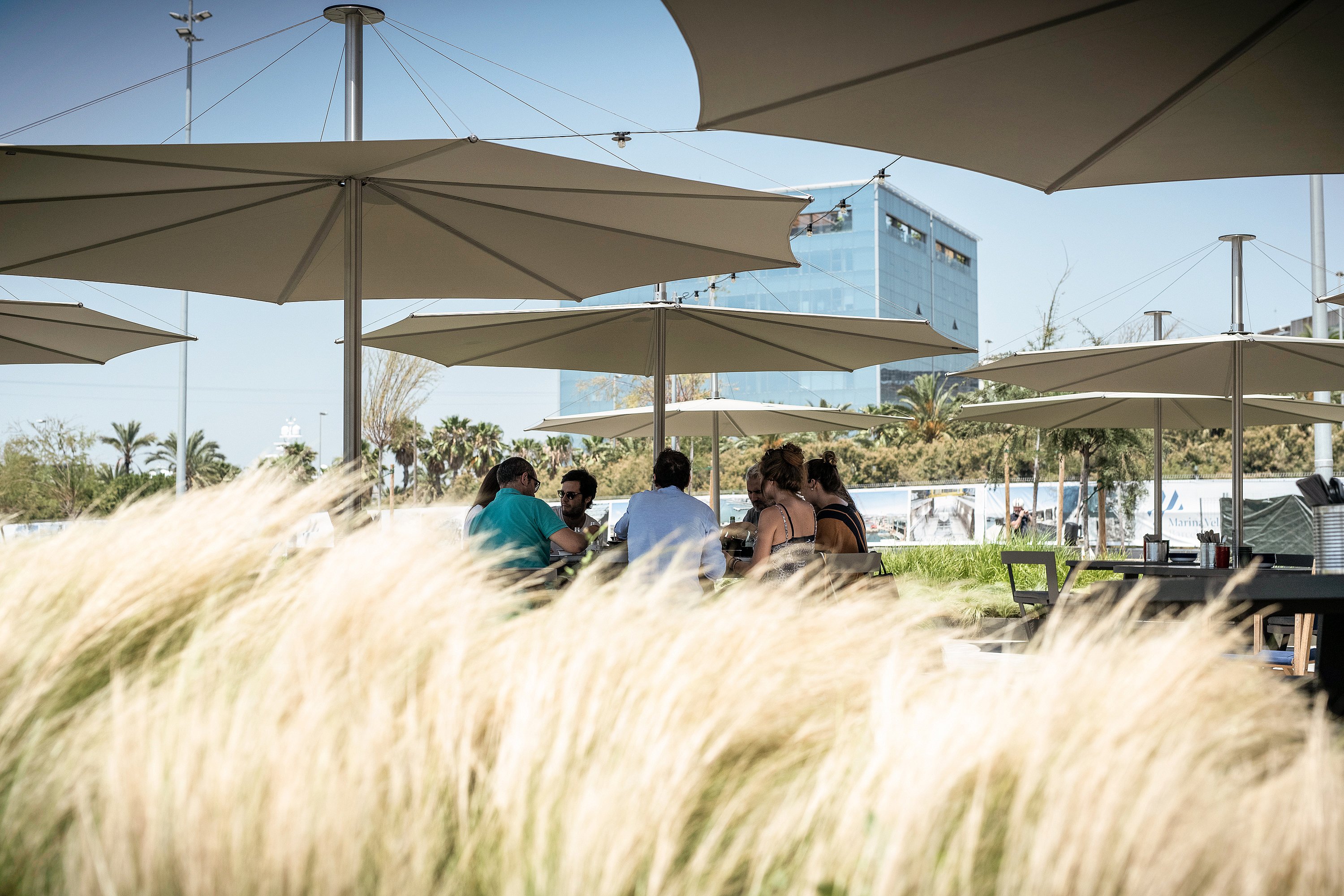 “Outdoor dining terrace with round picnic tables and white parasols, creating a comfortable social setting for meals and conversation.”
