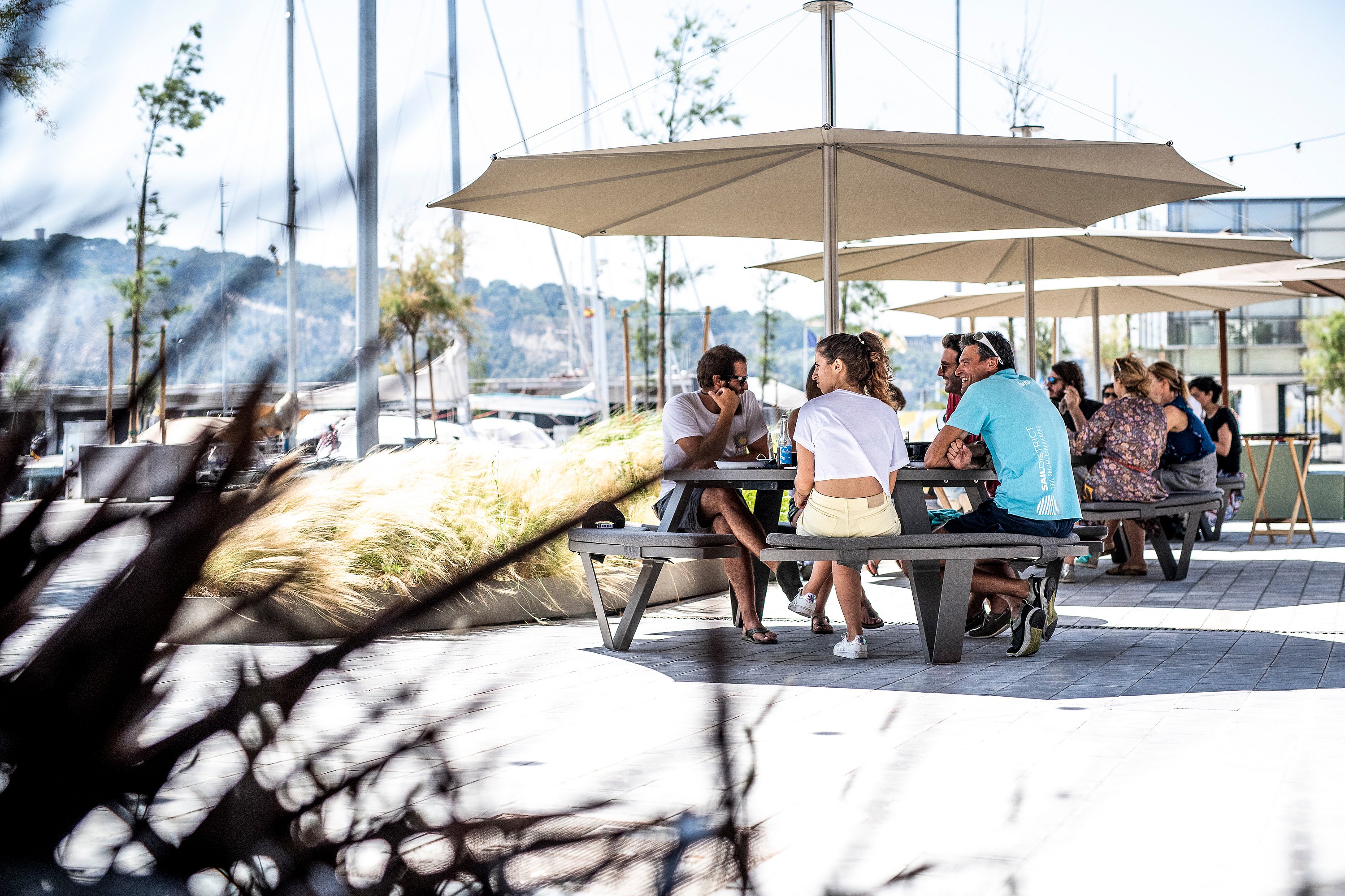 “Guests seated around a round Pantagruel table on the terrace, dining together in an open-air restaurant setting.”