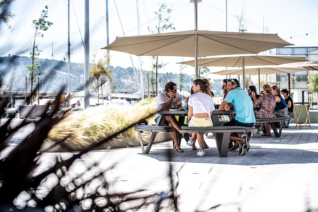 “Guests seated around a round Pantagruel table on the terrace, dining together in an open-air restaurant setting.”