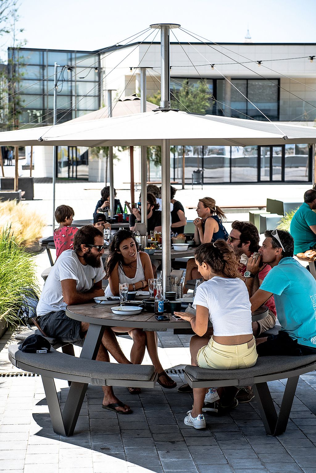 “Outdoor dining terrace with round picnic tables and white parasols, creating a comfortable social setting for meals and conversation.”