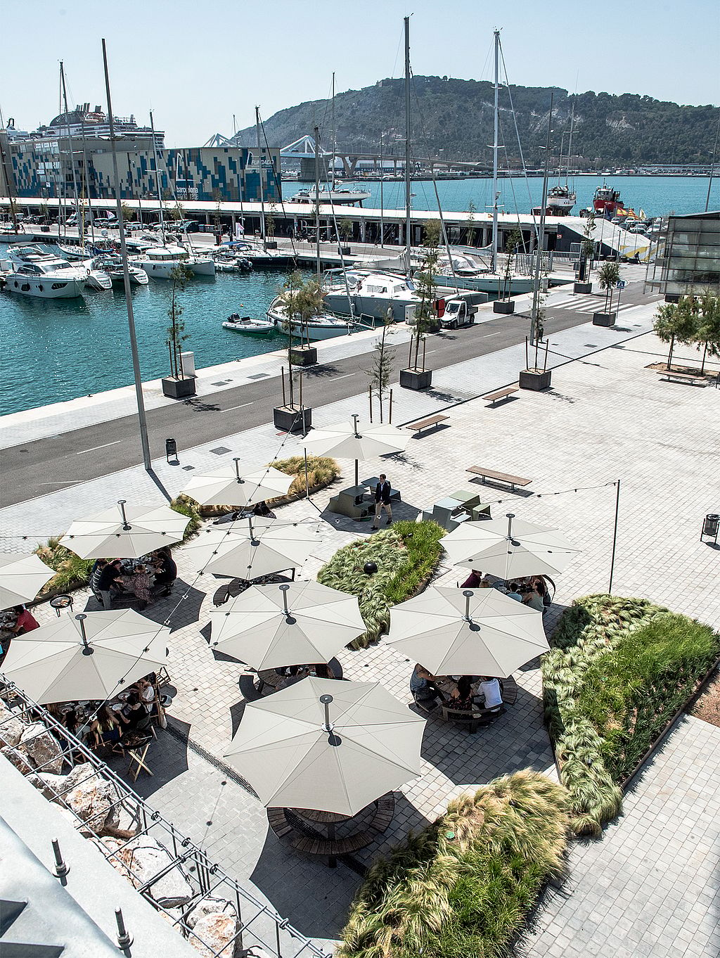 “Outdoor restaurant seating in Barcelona with durable round tables and parasols that remain outside year-round.”
