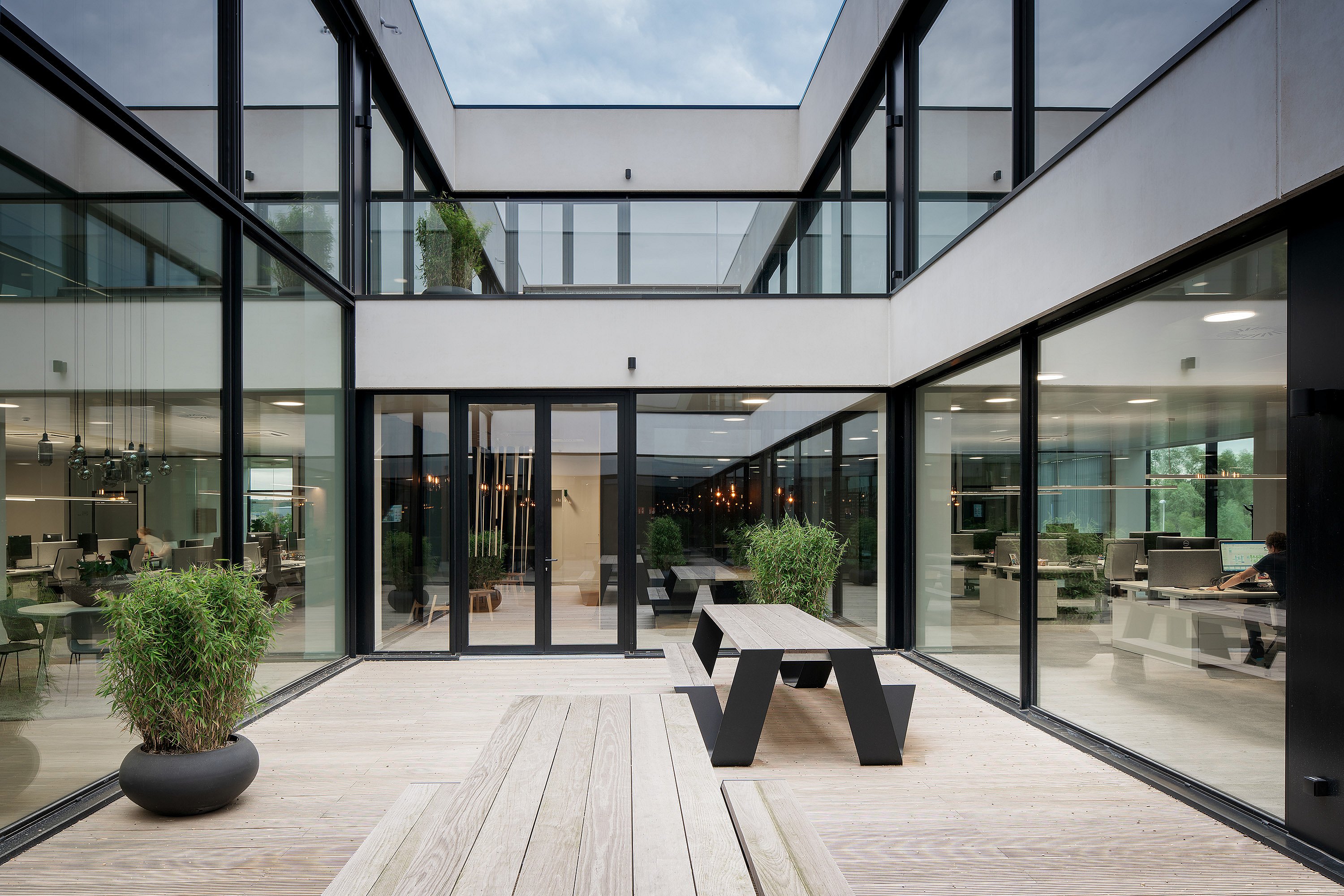 Office space with a central outdoor patio bringing natural light inside, furnished with Hopper picnic tables for informal working and meetings.