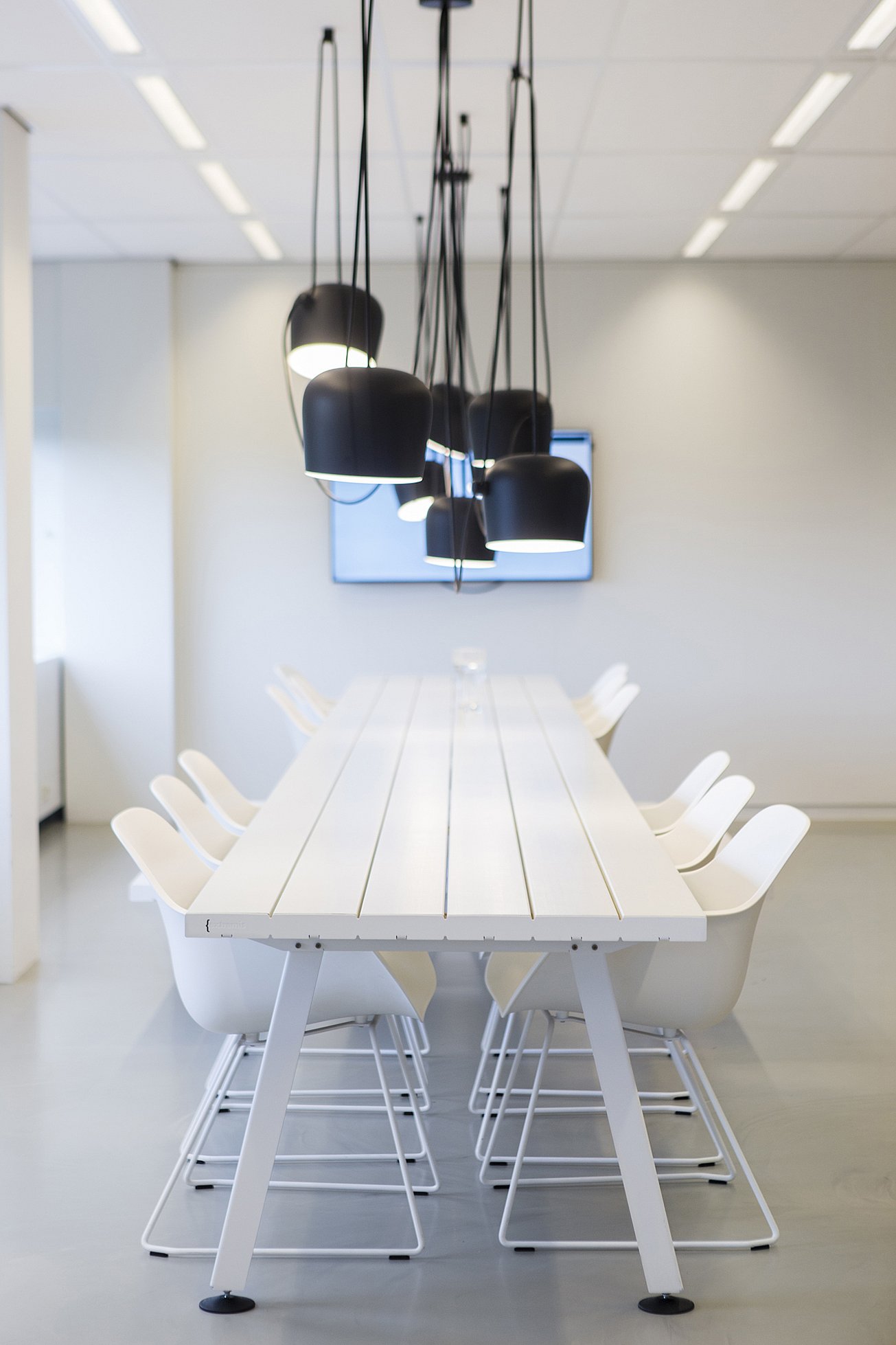 Moderne vergaderruimte in Centralpoint met een lange Marina Combo-tafel, omringd door witte Captain's Chairs en banken, in een lichte omgeving.