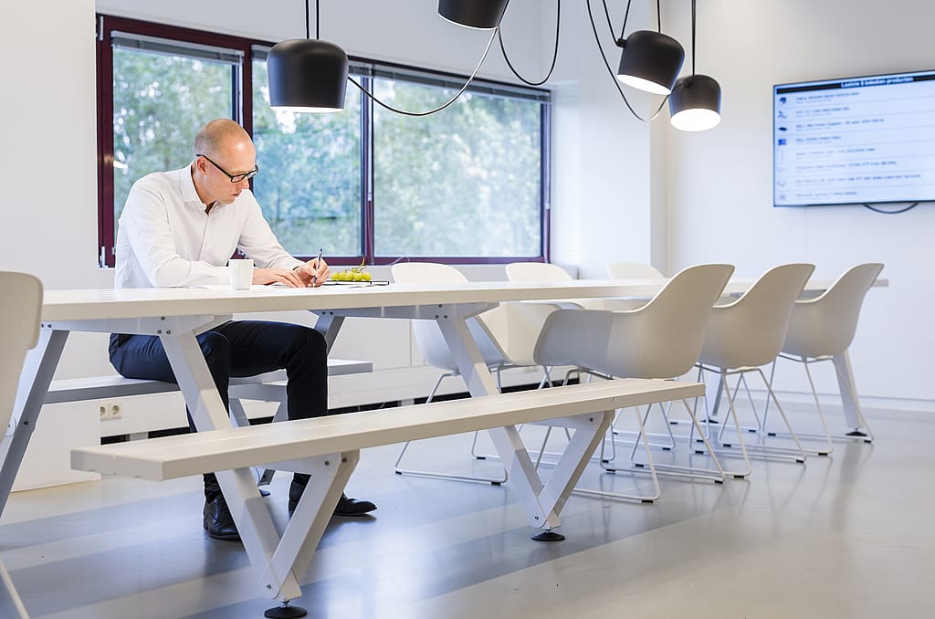 Colleagues seated around the Marina Combo table during a meeting, discussing work in a bright and modern office environment.