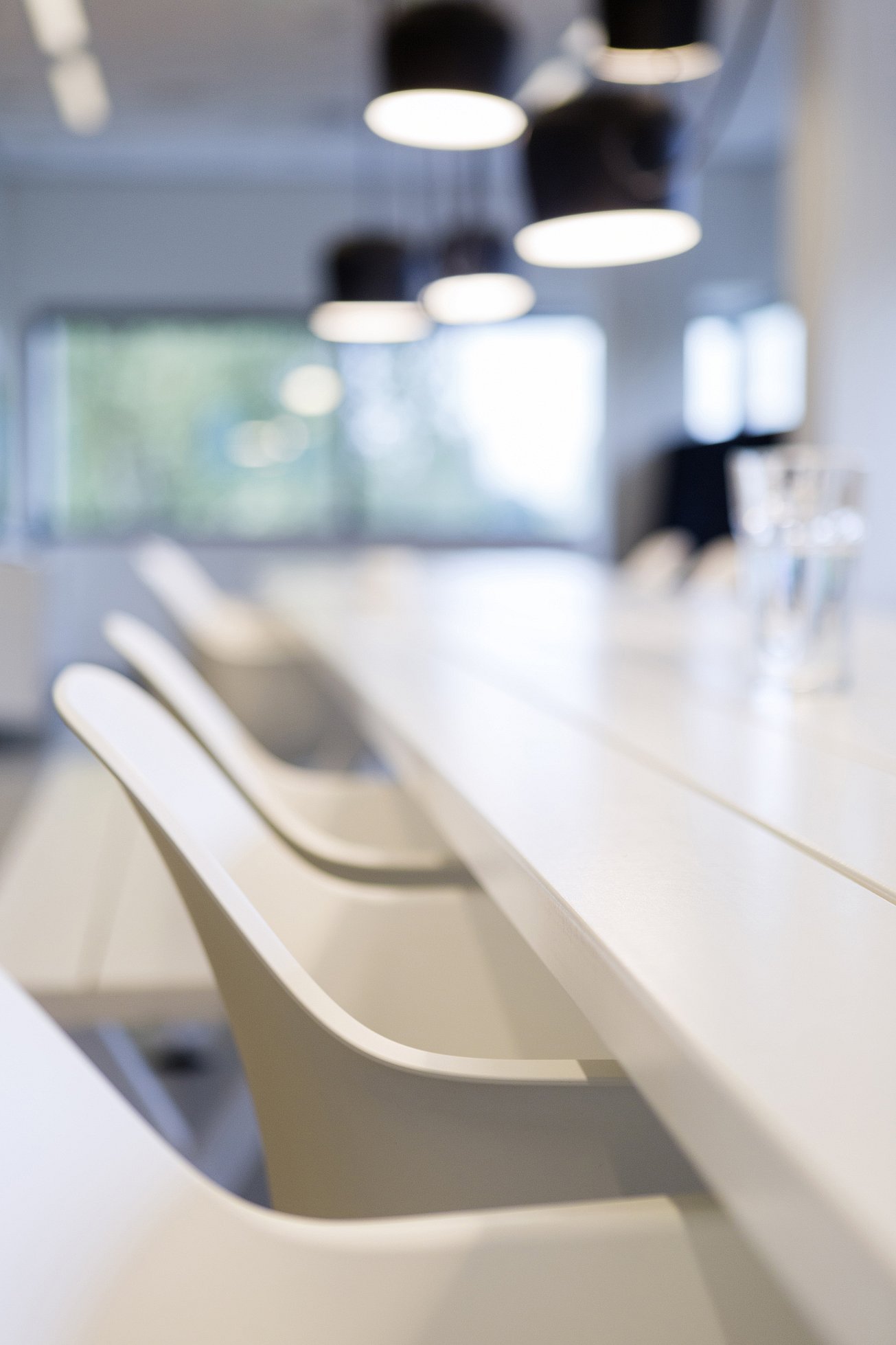 Detail view of white Captain’s Chairs placed around the Marina Combo table inside the office meeting space.