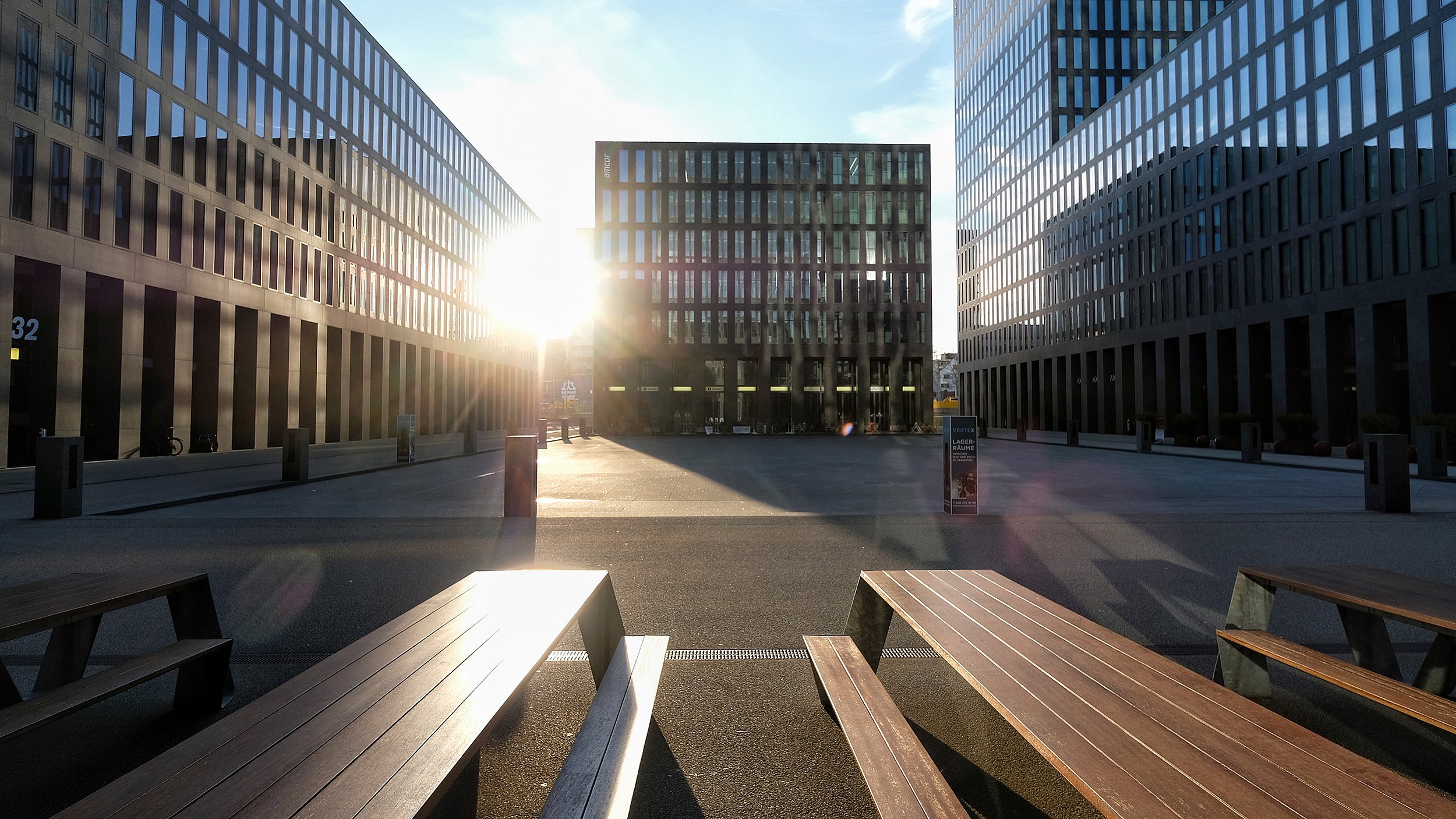 « Vue angulaire de la tour de bureaux du Credit Suisse et des gratte-ciel environnants, avec des tables Hopper au premier plan mettant en valeur les lignes architecturales épurées de la place. »