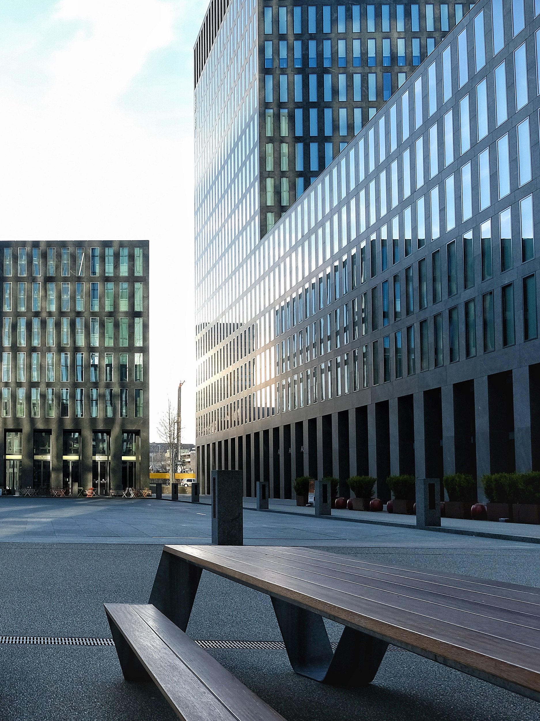 « Immeuble de bureaux moderne avec façade en verre réfléchissant dominant la zone de sièges extérieure dans le quartier d’Oerlikon à Zurich. »