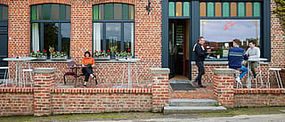 Guests gathered around a tiki table as high as a cocktail. Some sat on bar stools and others were in a lively bistro. '