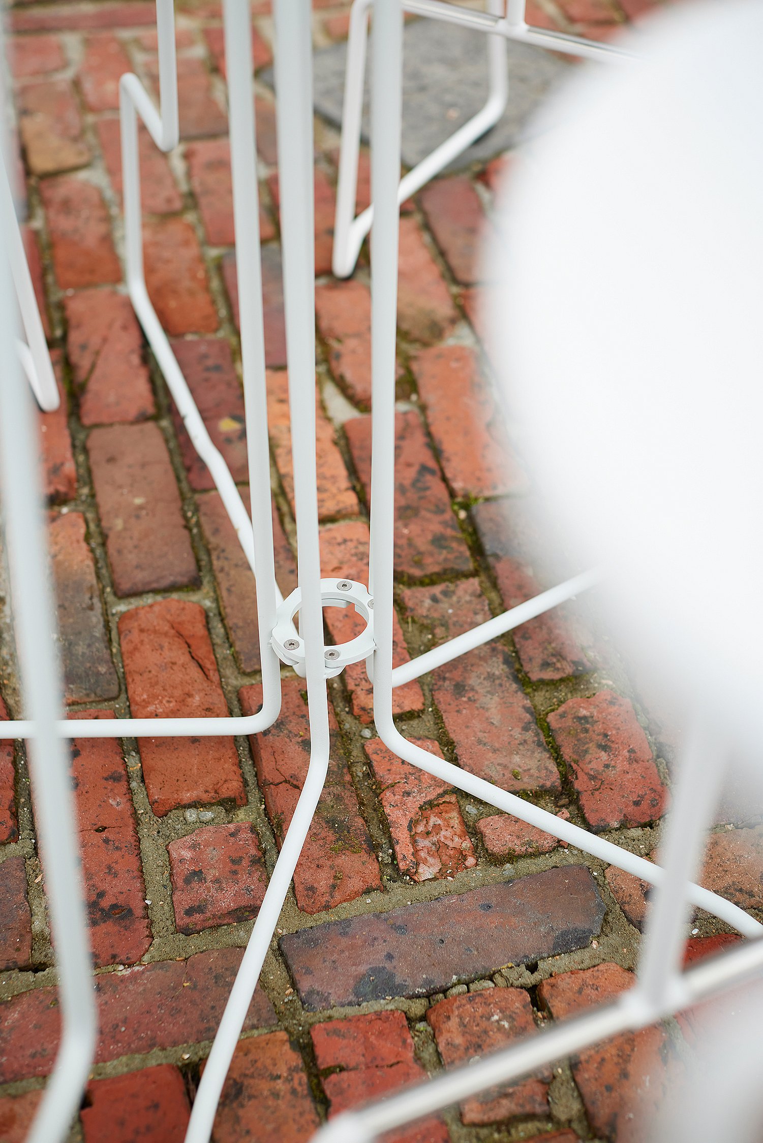 “Close-up of a tiki cocktail table with slender white legs and integrated footrest, designed for relaxing use while standing or sitting. ”
