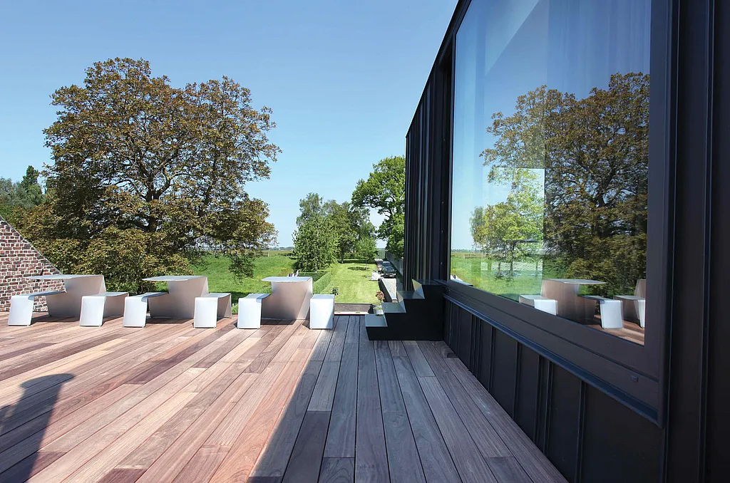 Minimalistische Büroterrasse in einem Architektenatelier in Riemst, ausgestattet mit Picnik-Picknicktischen, die den Arbeitsbereich im Freien in einer ruhigen, modernen Umgebung erweitern.