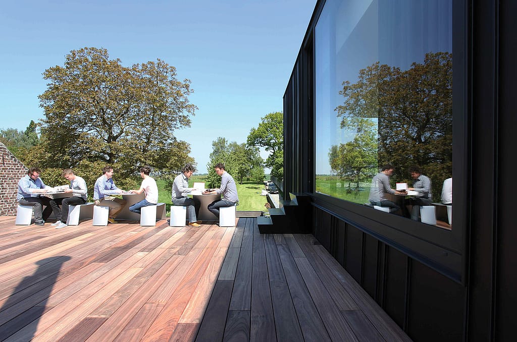 Contemporary office exterior where elegant Picnik tables create a practical outdoor workspace for employees to gather, meet, and have lunch