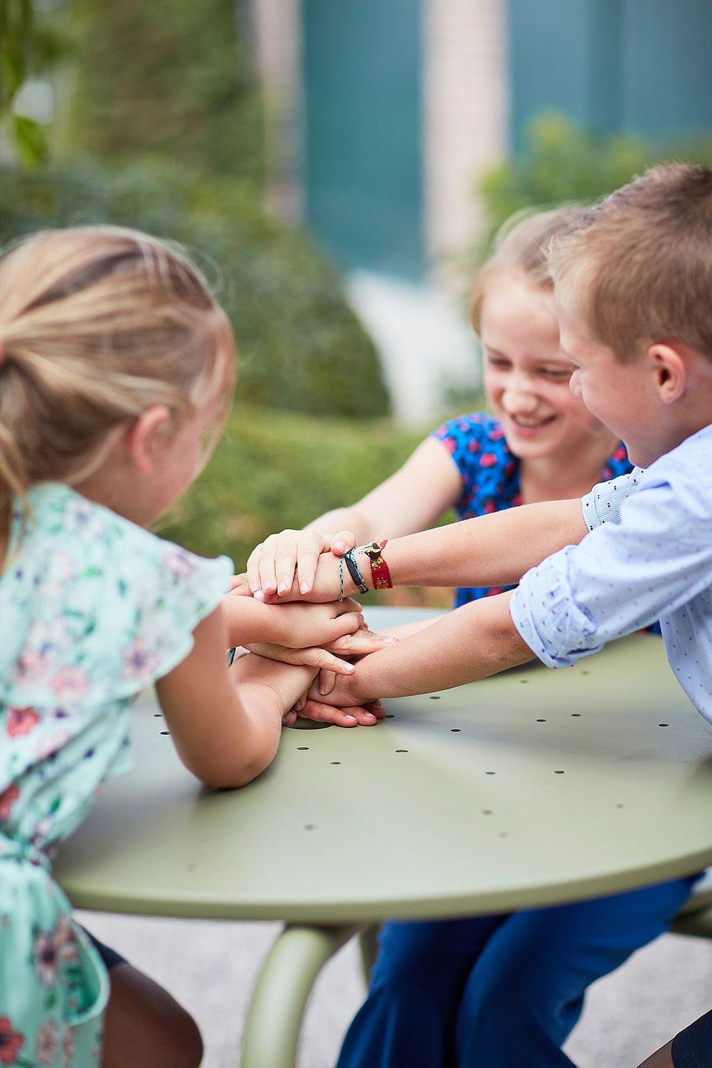 Playful outdoor setting with colorful Virus tables inviting children and adults to sit together in a cheerful holiday-house garden.
